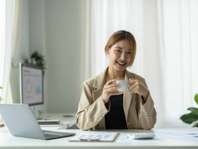 Portrait of young beautiful asian businesswoman looking at camera and smile, arms crossed in modern office workplace.