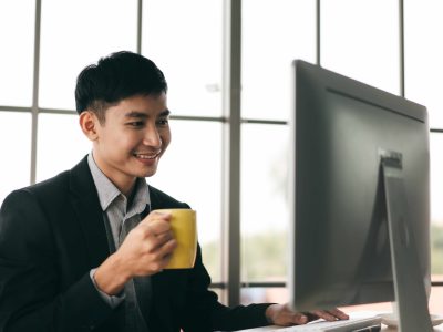 Portrait of happy smile office business asian salary man working and relax with coffee cup. Workplace with document and computer. He hold paper on a desk with coffee cup. Background with window light.