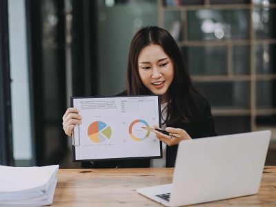 Cheerful business lady working on laptop in office, Asian happy beautiful businesswoman in formal suit work in workplace. Attractive female employee office worker smile.
